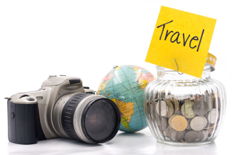 Coins in glass bottle with camera and globe on white background,